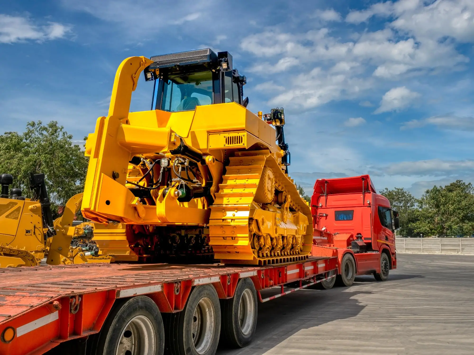 Tractor oruga amarillo asegurado sobre una plataforma baja (lowboy) remolcada por un tractocamión.